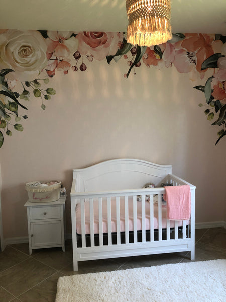 Charlotte watercolor flower canopy wall decal arching above a white nursery crib