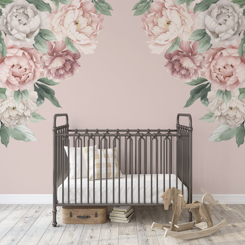 Pink and white watercolor peony corner wall decals framing a dark metal crib on a blush nursery wall