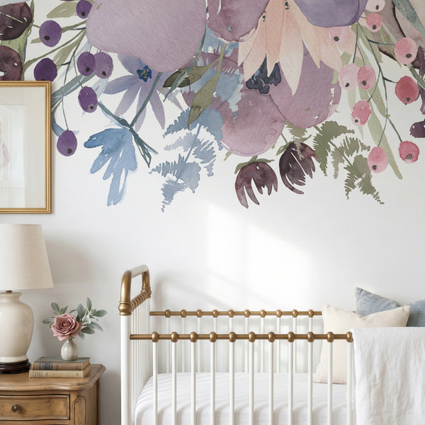 Pink and lavender watercolor flower wall decals arranged above a white crib in a nursery
