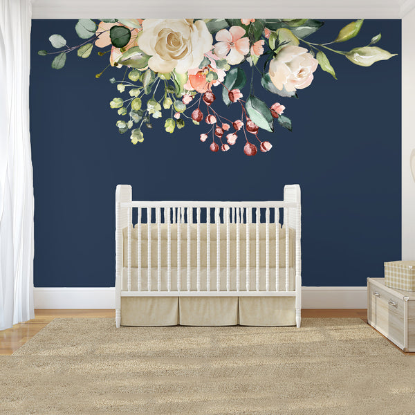 GAIA pale flowers and greenery above a white crib on a navy nursery wall
