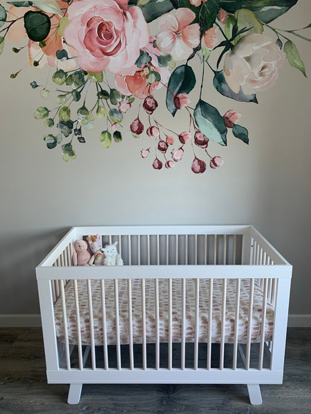 Pink and cream GAIA flower arrangement above a white crib against a dark wall